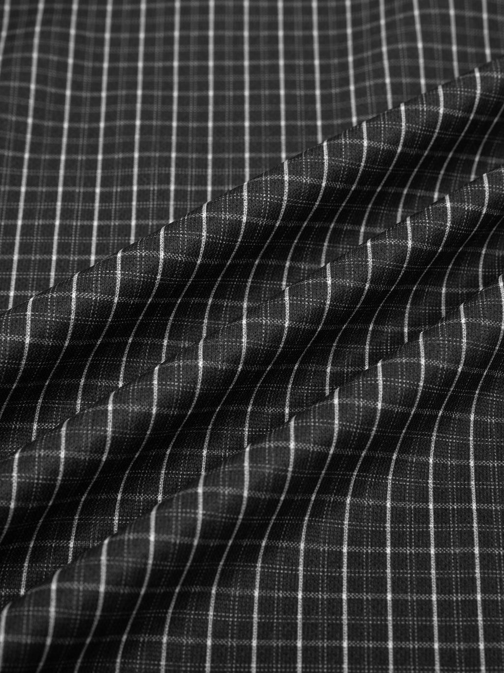 Close-up of black and white contrast plaid fabric, showing cotton-polyester blend texture and subtle folds.