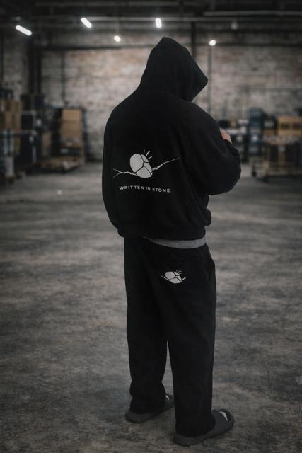 Unisex oversized black raglan hoodie and sweatpants with "Written in Stone" graphic.