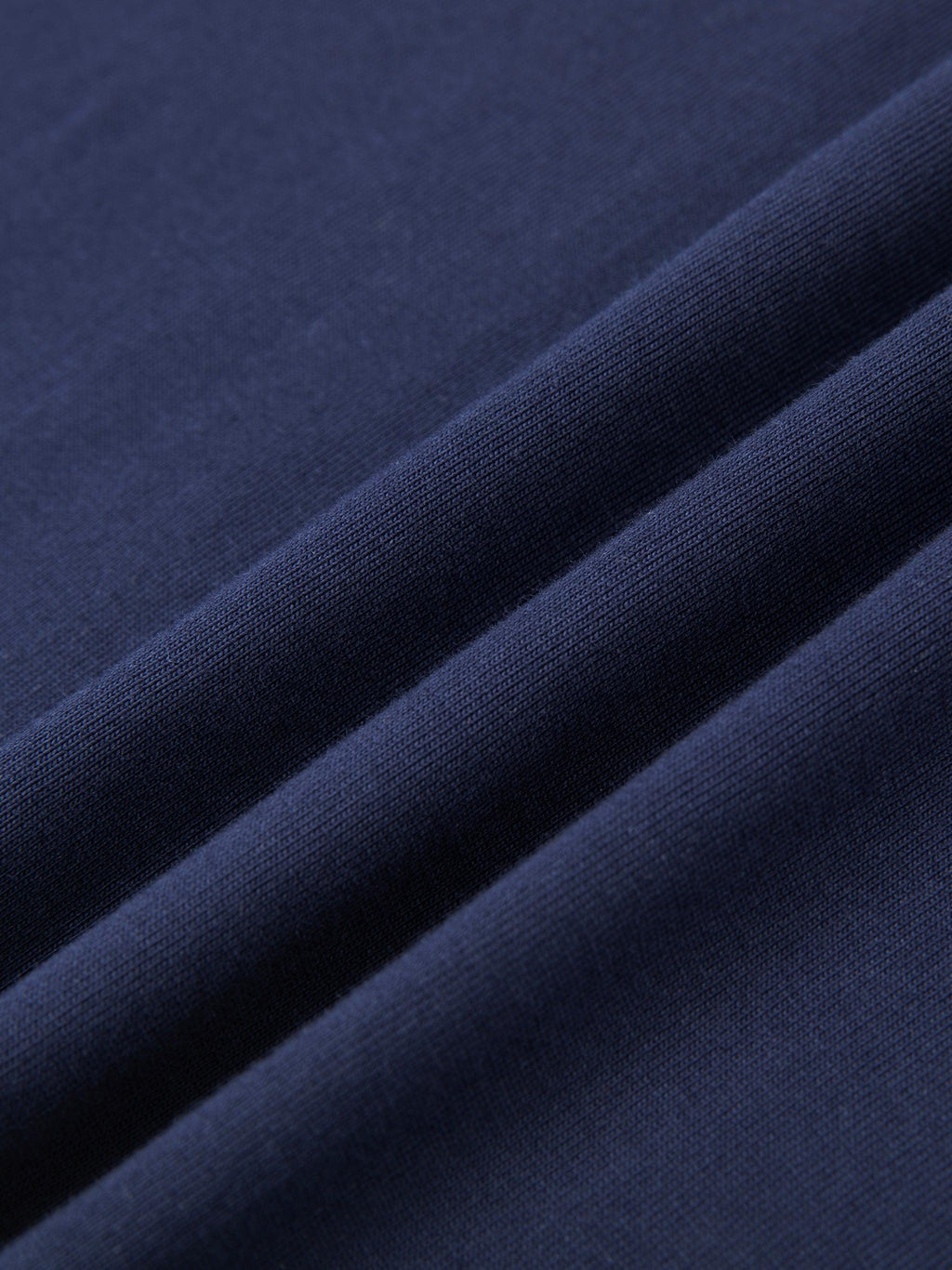 Close-up of a folded navy blue 100% cotton t-shirt, showcasing its soft, regular fabric texture.
