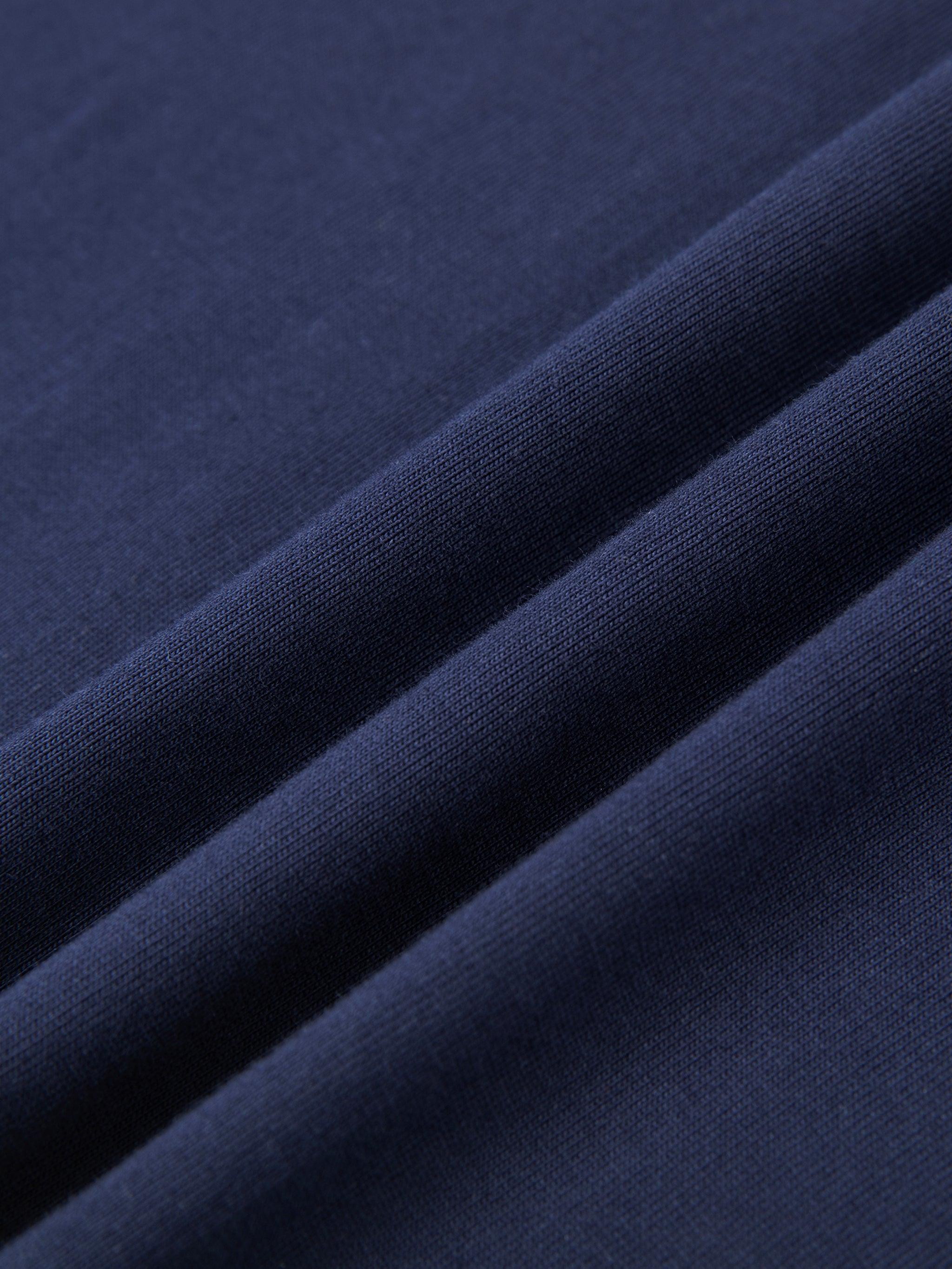Close-up of a folded navy blue 100% cotton t-shirt, showcasing its soft, regular fabric texture.