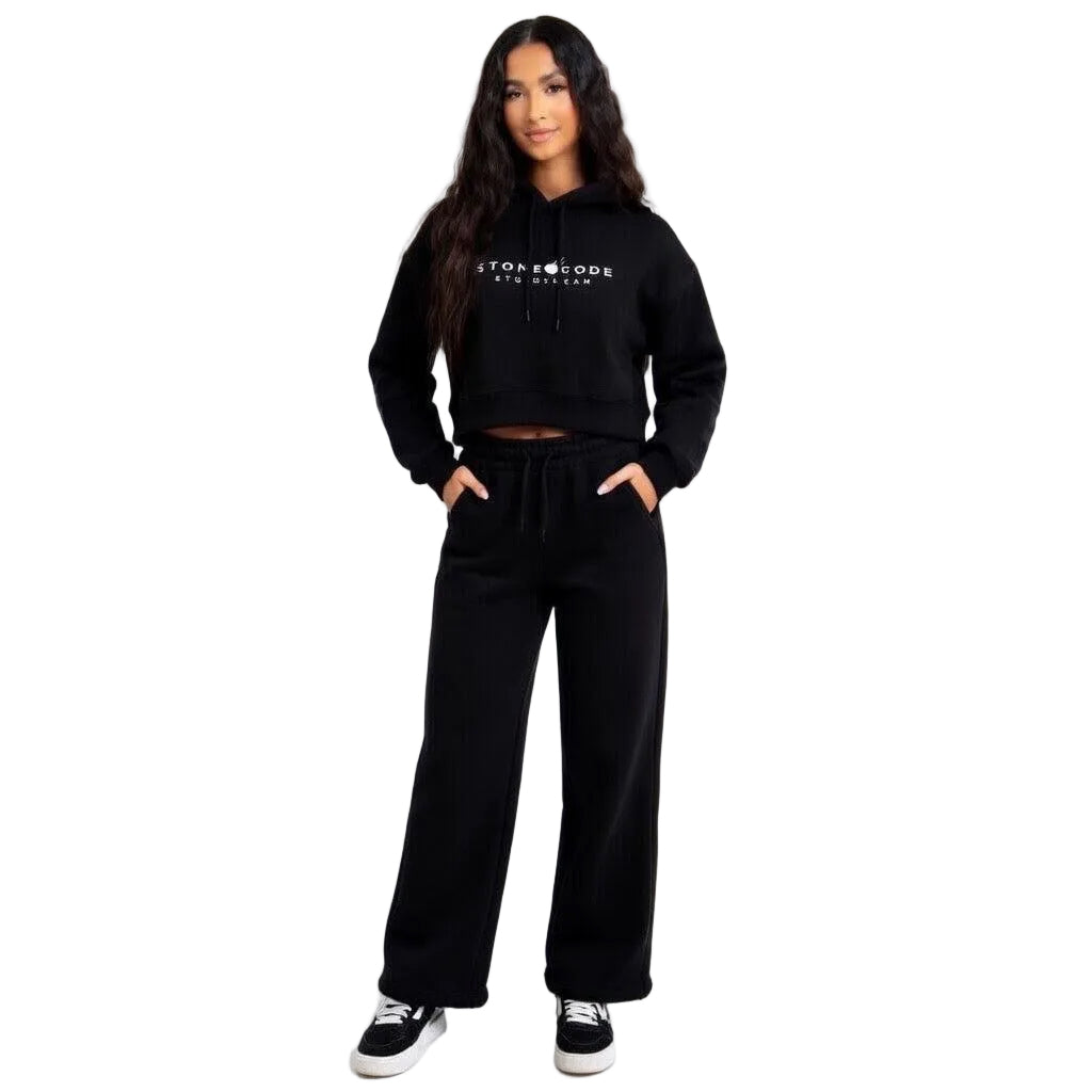 Woman wearing a black cropped hoodie with white logo print and matching wide-leg sweatpants.