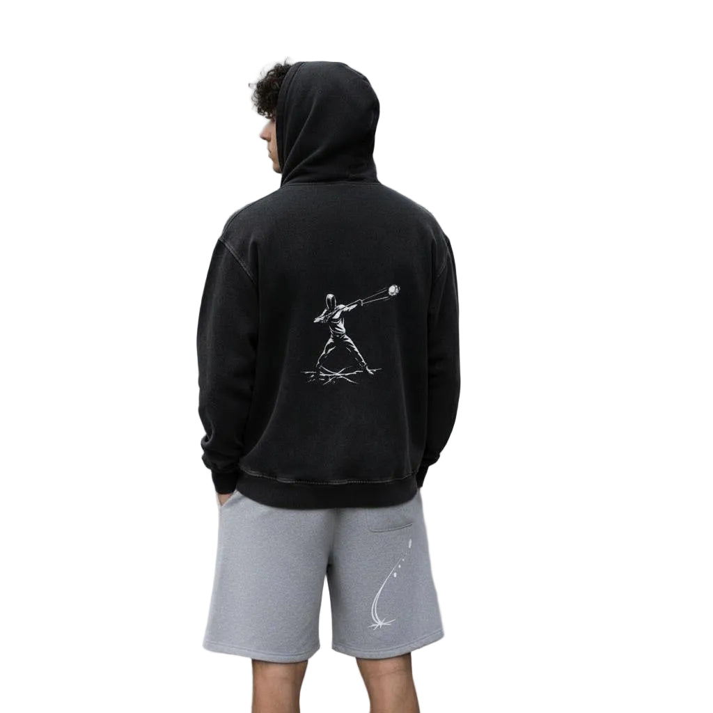 Unisex model wearing a black heavyweight fleece hoodie with a white graphic print on the back and gray fleece shorts with a white graphic.