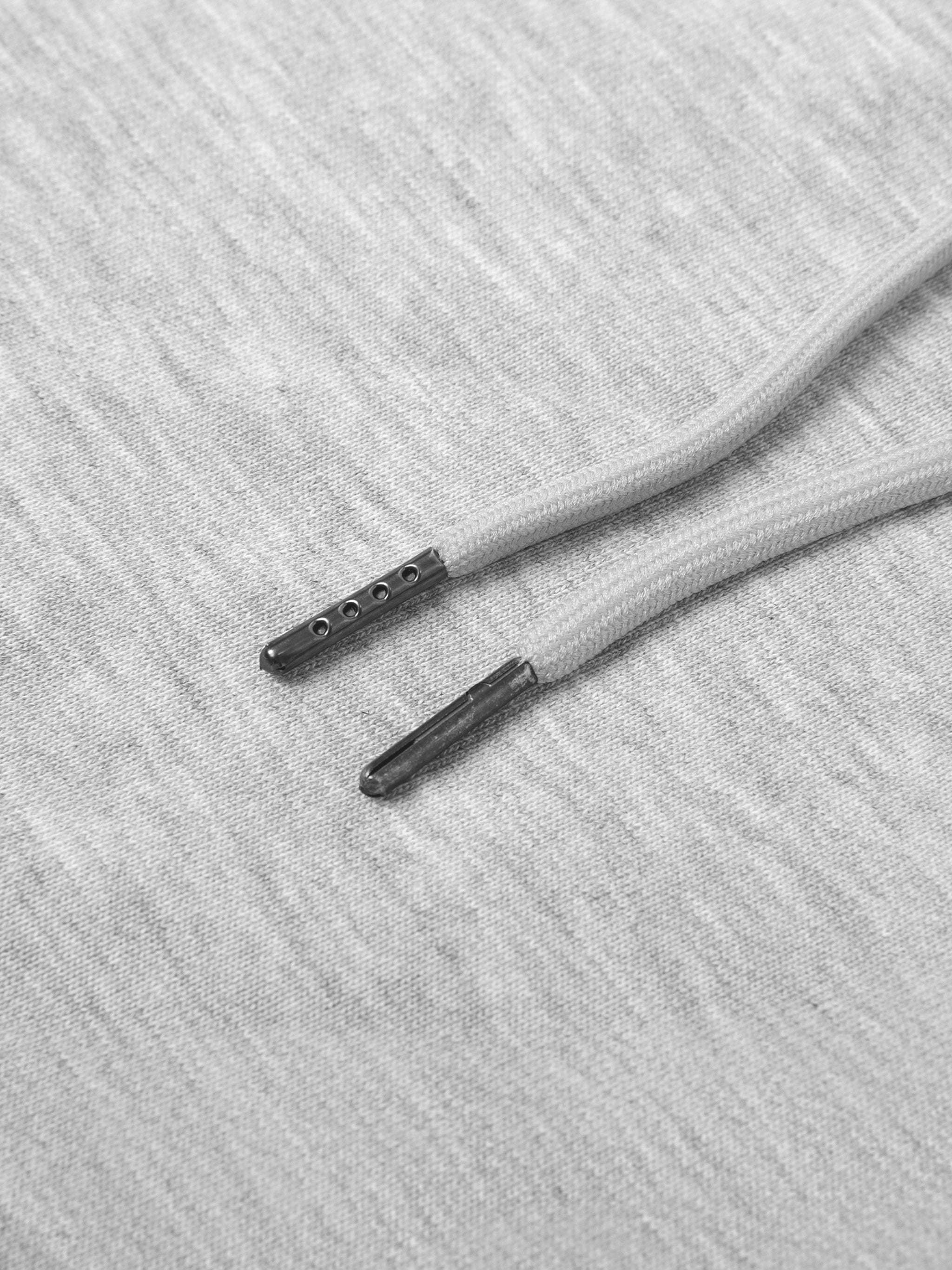 Close-up of light gray cotton blend sweatpants with a drawstring and metal aglets.