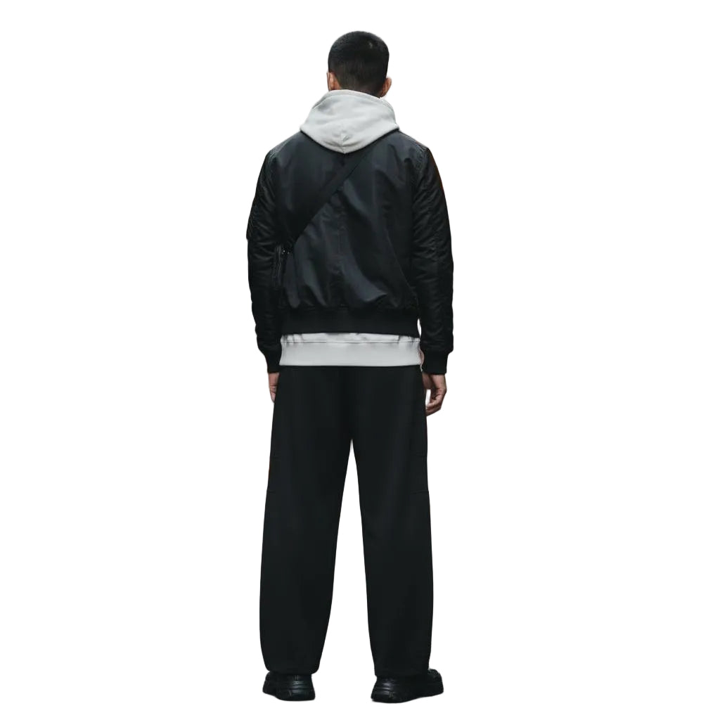Unisex model wearing black heavyweight wide leg panel sweatpants, a black bomber jacket, and a light gray hoodie.