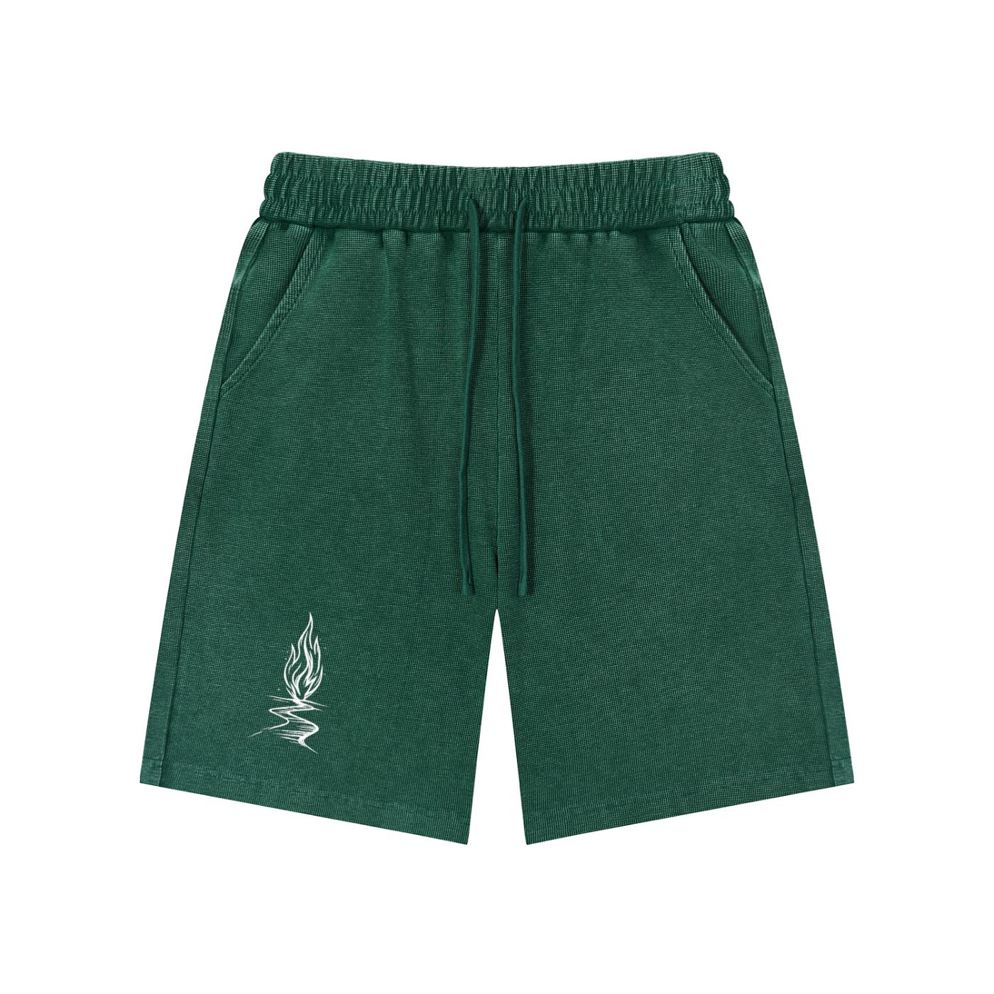Unisex mineral wash waffle knit shorts in dark green with drawstring waist, pockets, and a white flame graphic.