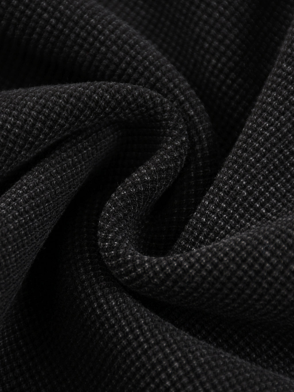 Close-up of black mineral wash waffle knit fabric, showcasing the textured cotton blend material.