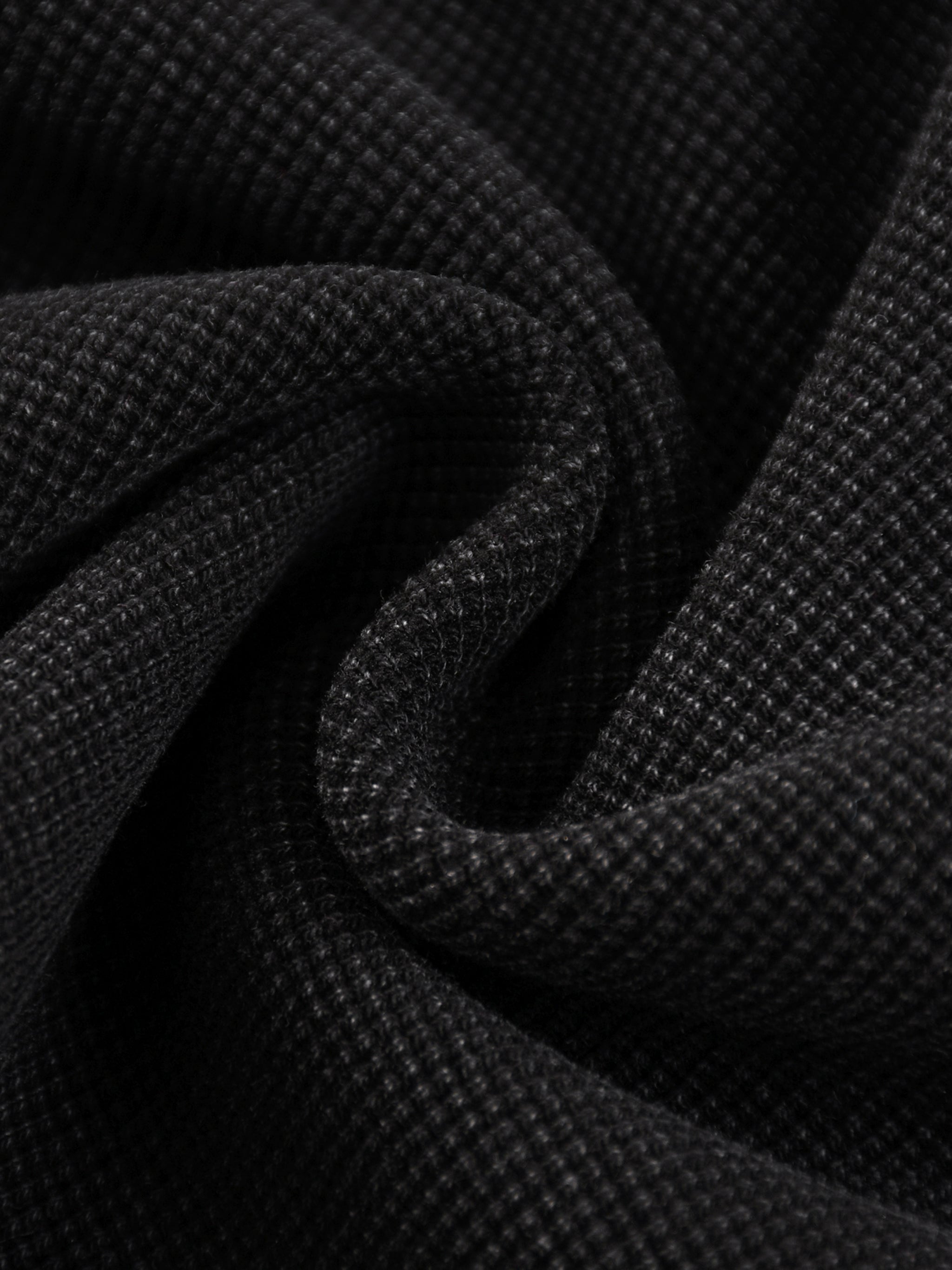 Close-up of black mineral wash waffle knit fabric, showcasing the textured cotton blend material.