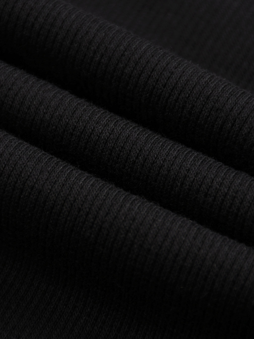 Close-up of black mineral wash waffle knit fabric, showing texture and folds.