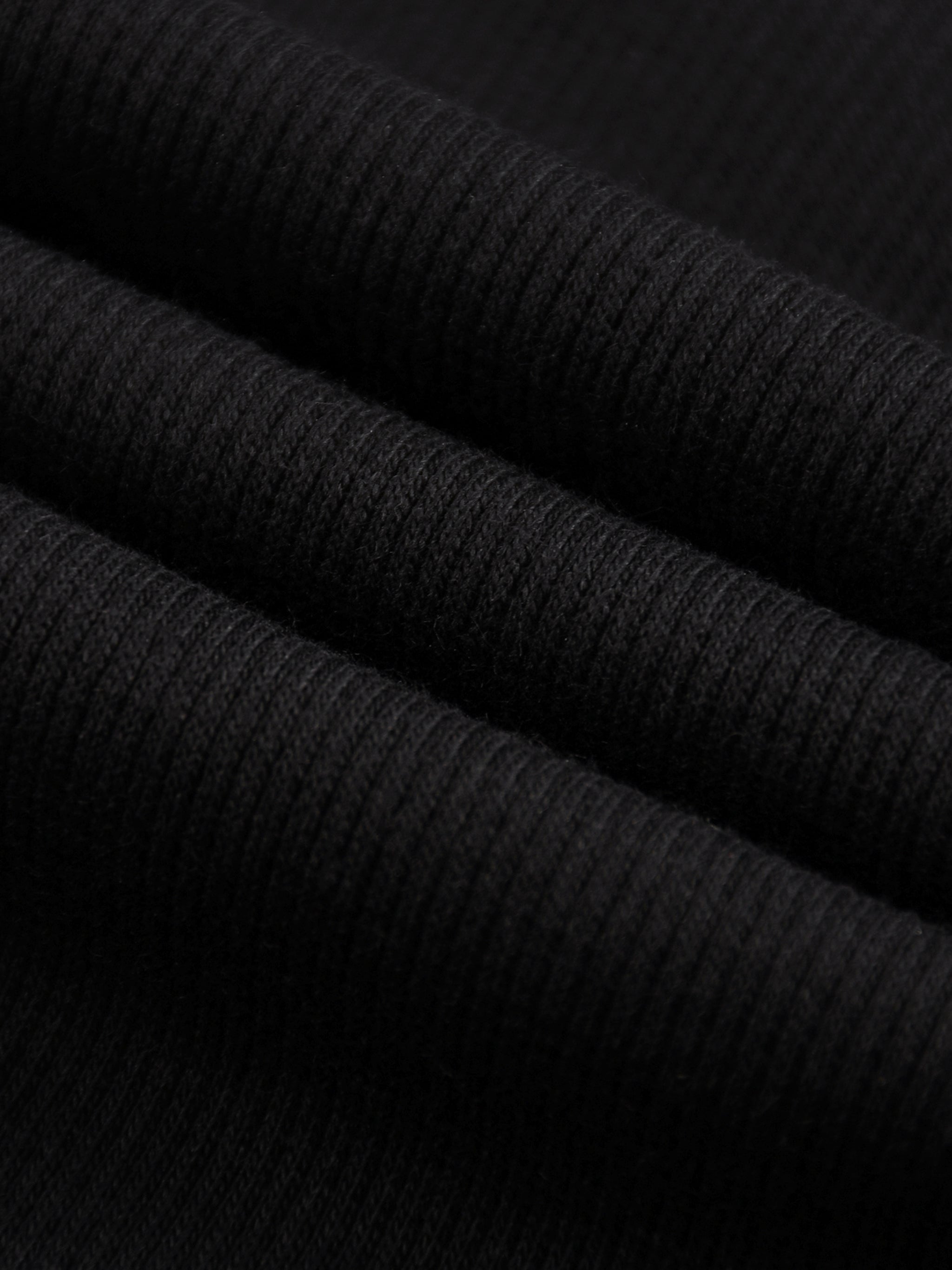 Close-up of black mineral wash waffle knit fabric, showing texture and folds.