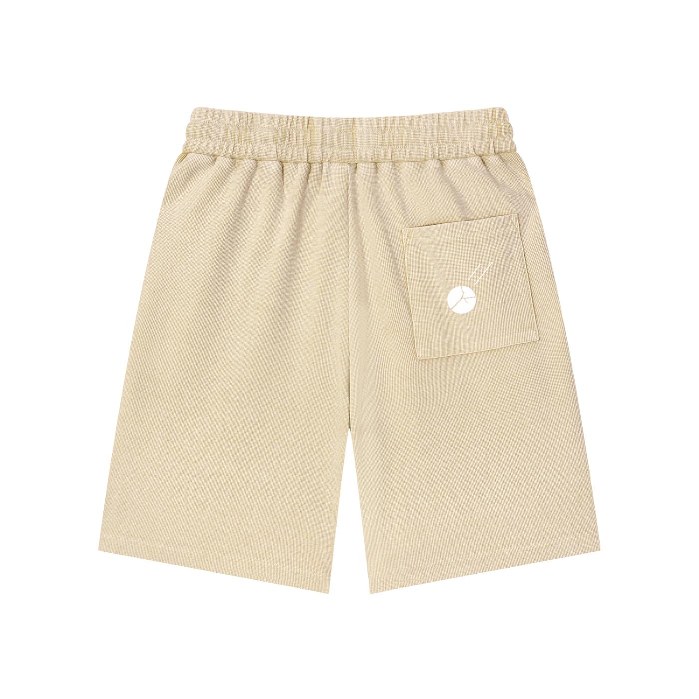 Mineral wash waffle knit shorts in beige with an elastic waistband and a single back pocket featuring a white graphic.