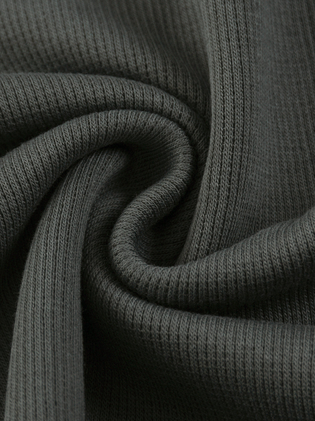 Close-up of dark gray mineral wash waffle knit fabric, showing ribbed texture and soft folds.