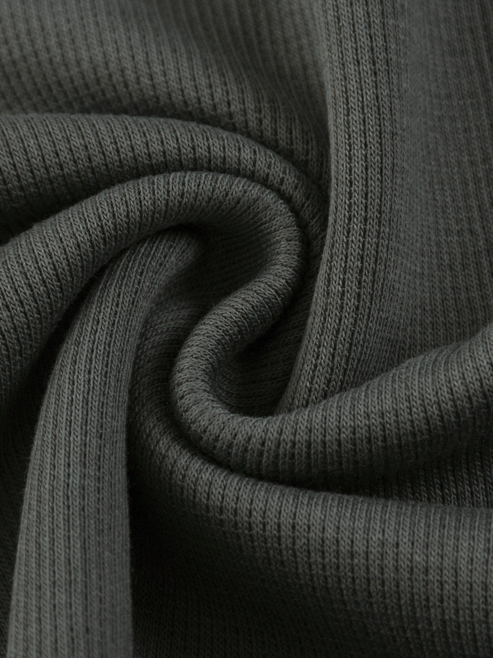 Close-up of dark gray mineral wash waffle knit fabric, showing ribbed texture and soft folds.