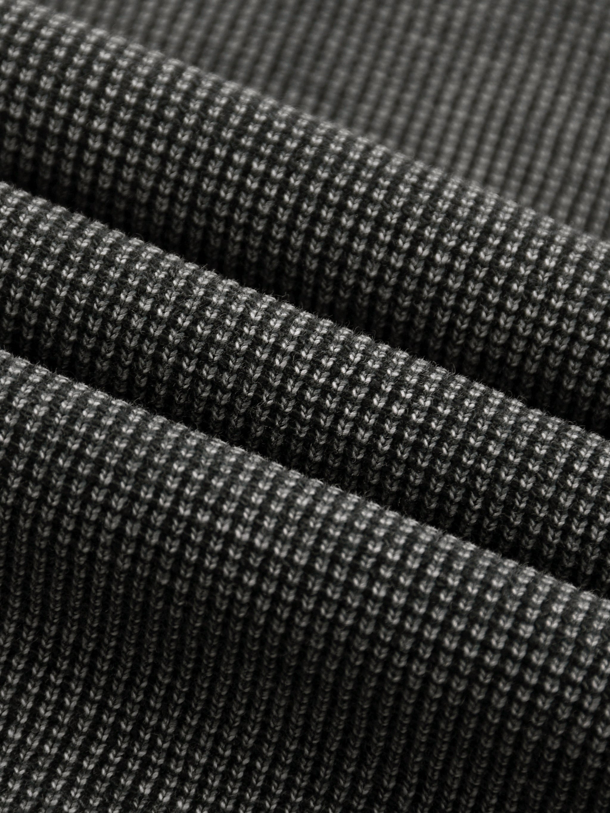Close-up of a dark grey mineral wash waffle knit t-shirt fabric, showing its textured cotton blend.