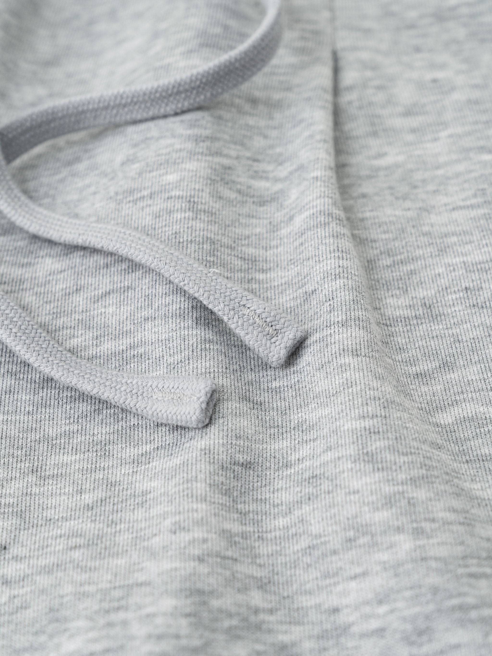 Close-up of light gray cotton-polyester blend fabric with a drawstring, showing texture.