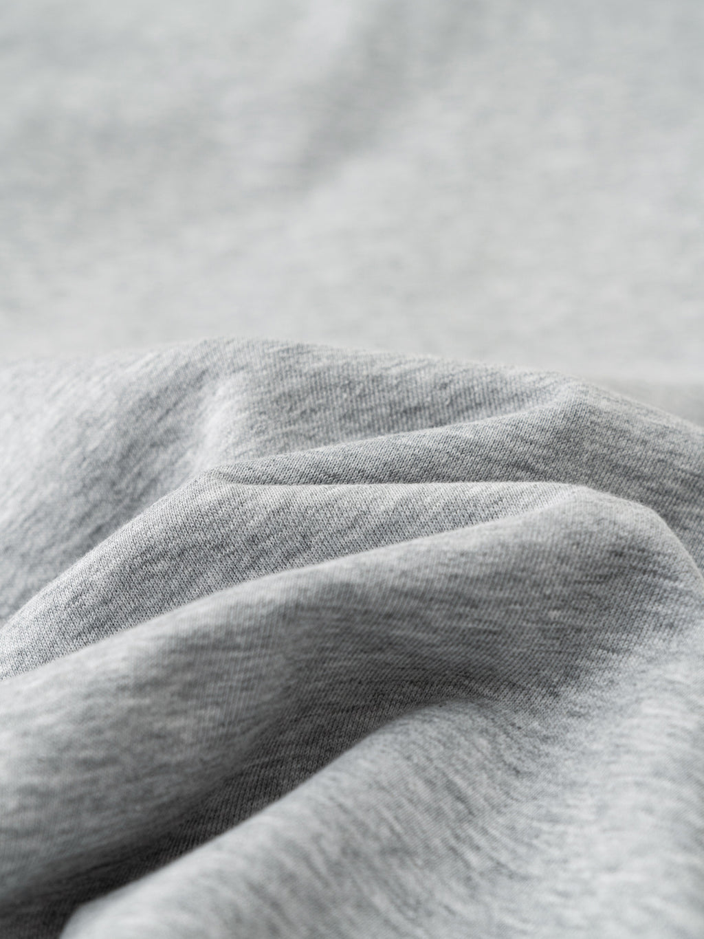 Close-up of soft, light gray cotton-polyester blend fabric with gentle folds, ideal for casual pants.