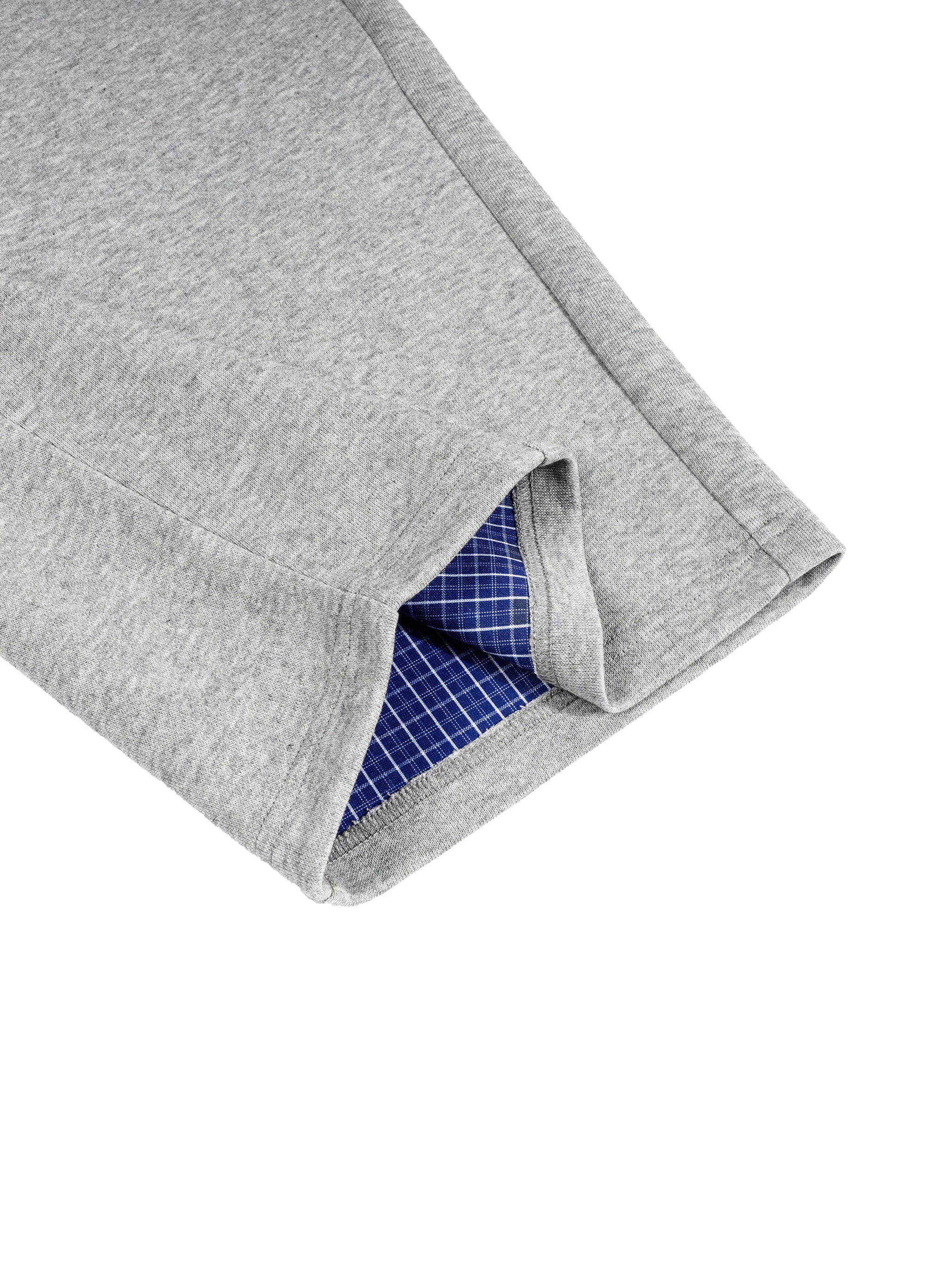 Close-up of gray barrel sweatpants with a blue and white plaid waistband detail.