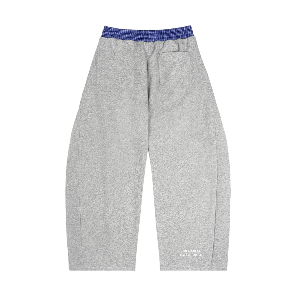 Loose fit gray barrel sweatpants with a blue plaid waistband and "PREPARED, NOT AFRAID." text on the lower leg.