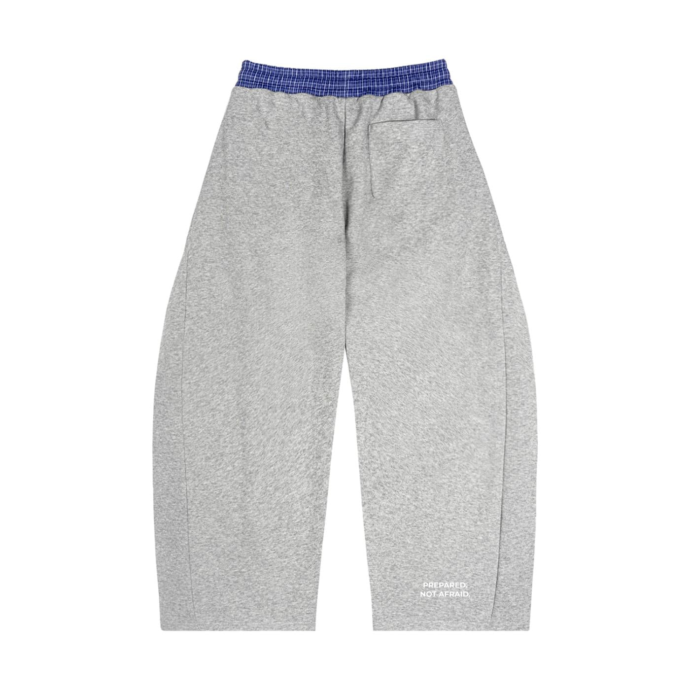 Loose fit gray barrel sweatpants with a blue plaid waistband and "PREPARED, NOT AFRAID." text on the lower leg.