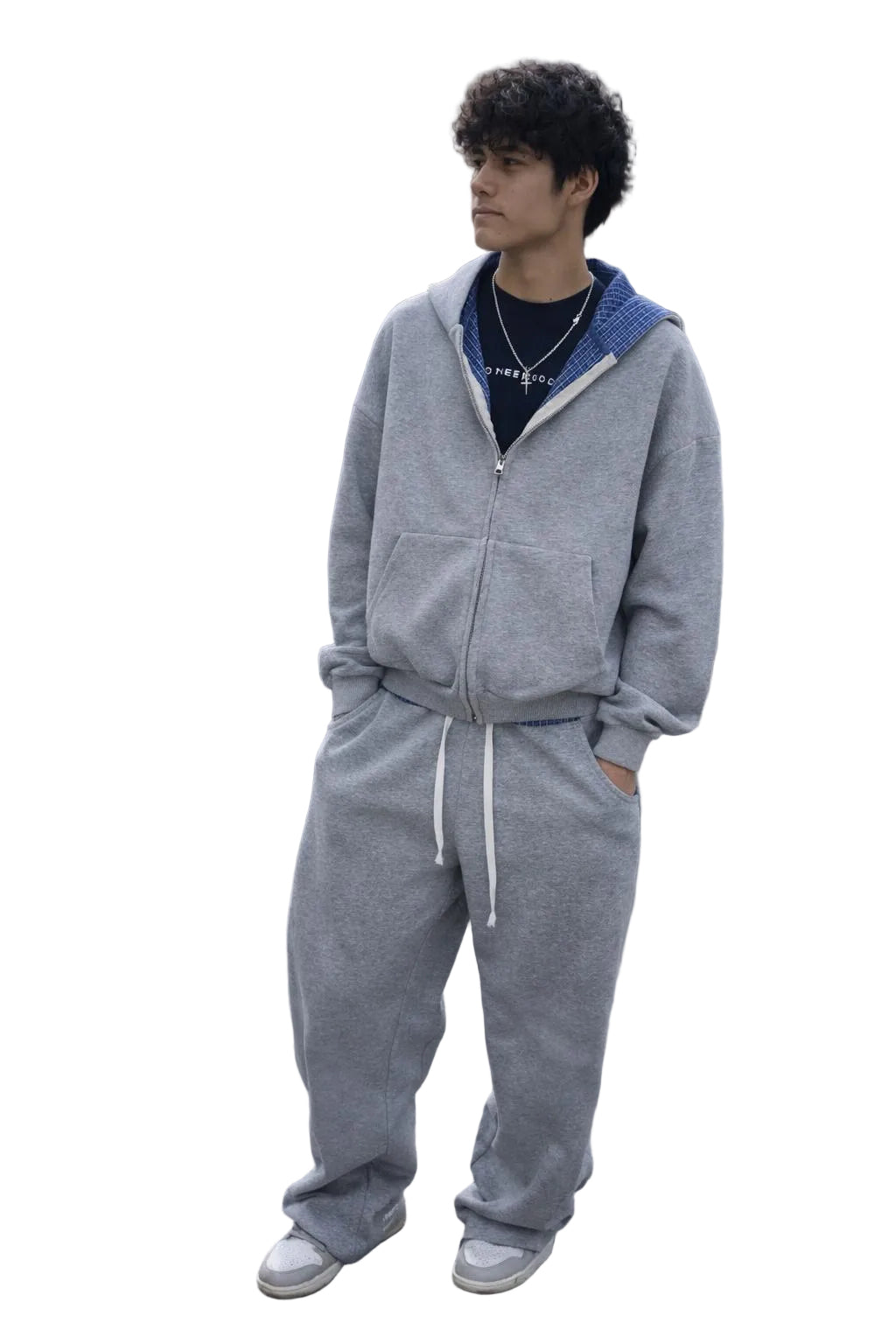 Unisex model wearing a gray cotton blend full-zip hoodie, matching barrel sweatpants with a plaid waistband, and a navy t-shirt.