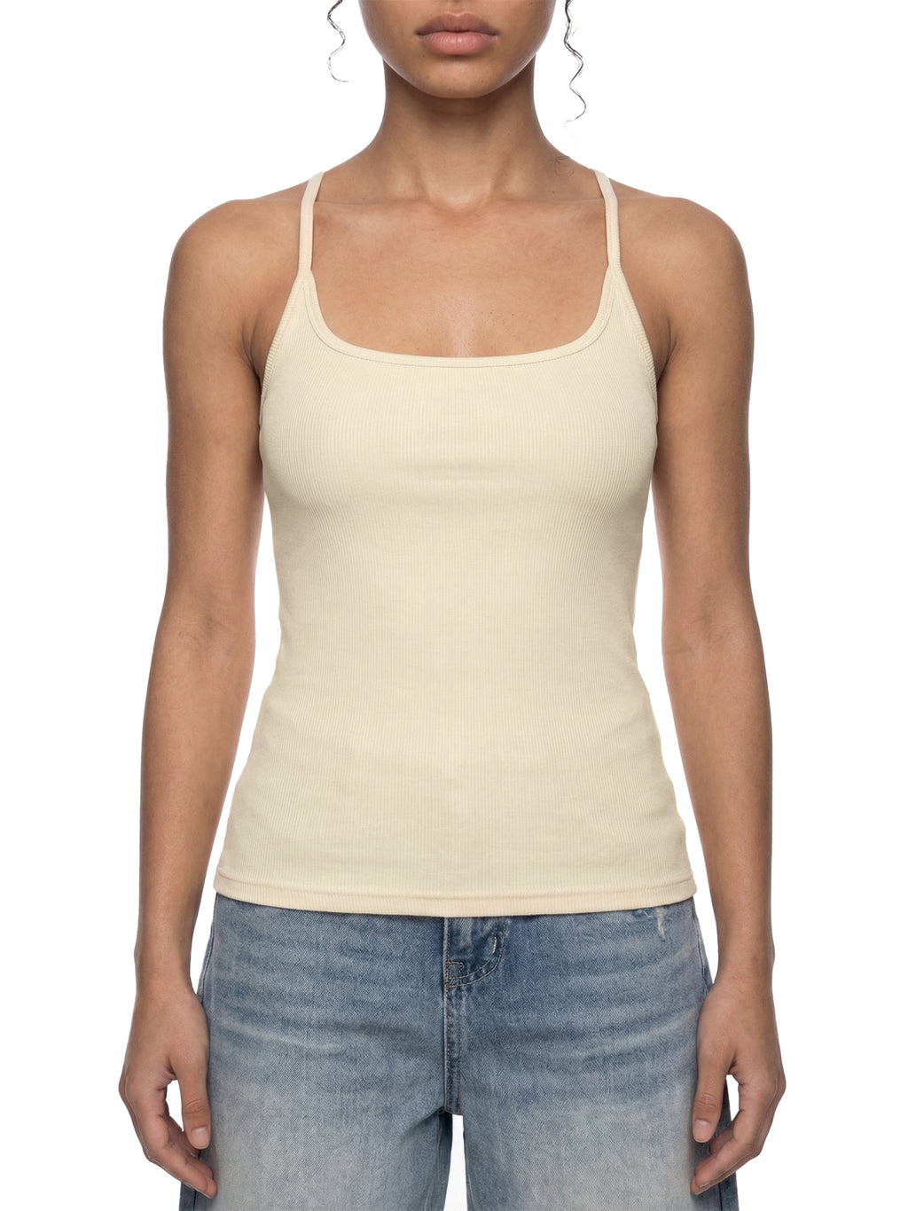 Model wearing a slim-fit, ribbed, cream racerback tank top made of cotton blend, paired with blue jeans.