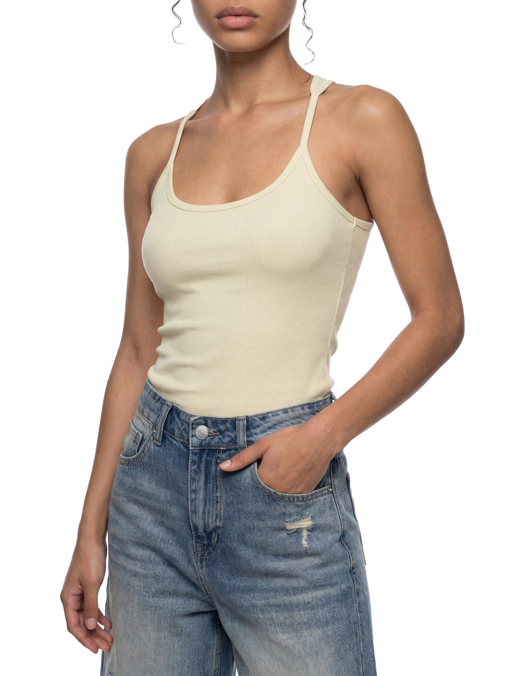 Woman wearing a slim fit, ribbed, light yellow racerback tank top with U-neck and blue denim jeans.