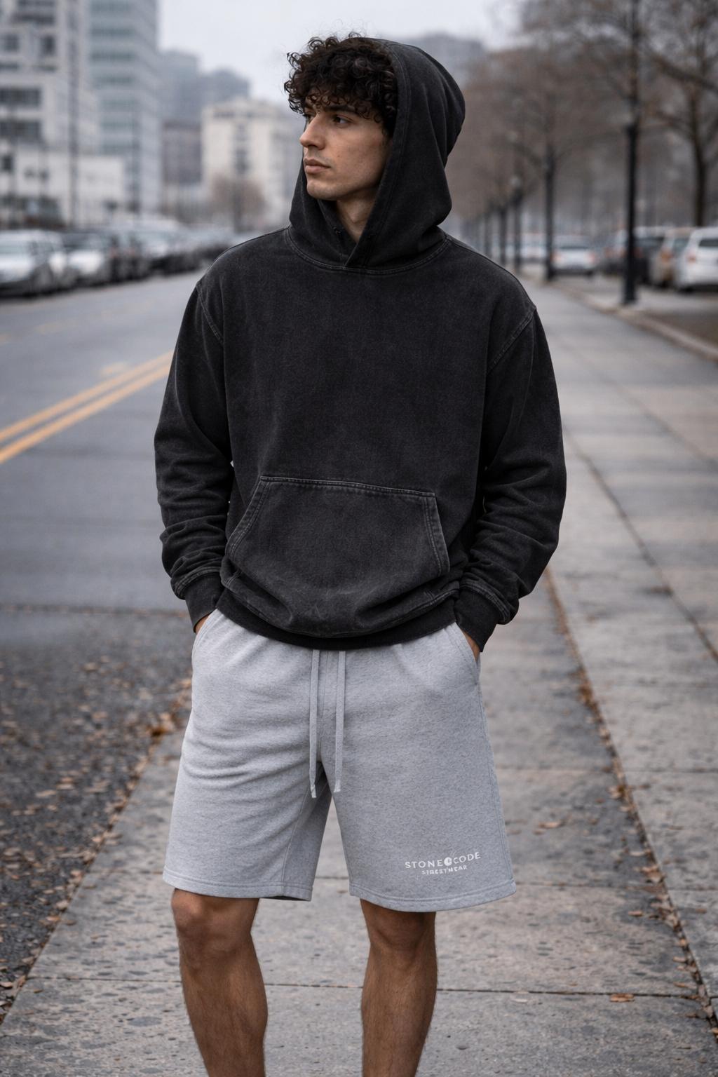 Unisex snow washed loose cotton hoodie in charcoal with a front pocket, worn by a man outdoors.