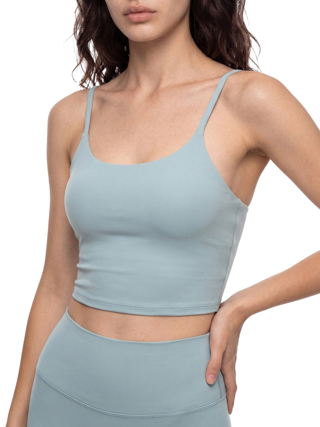 Light blue spaghetti strap crop yoga sports bra and matching leggings on a woman.