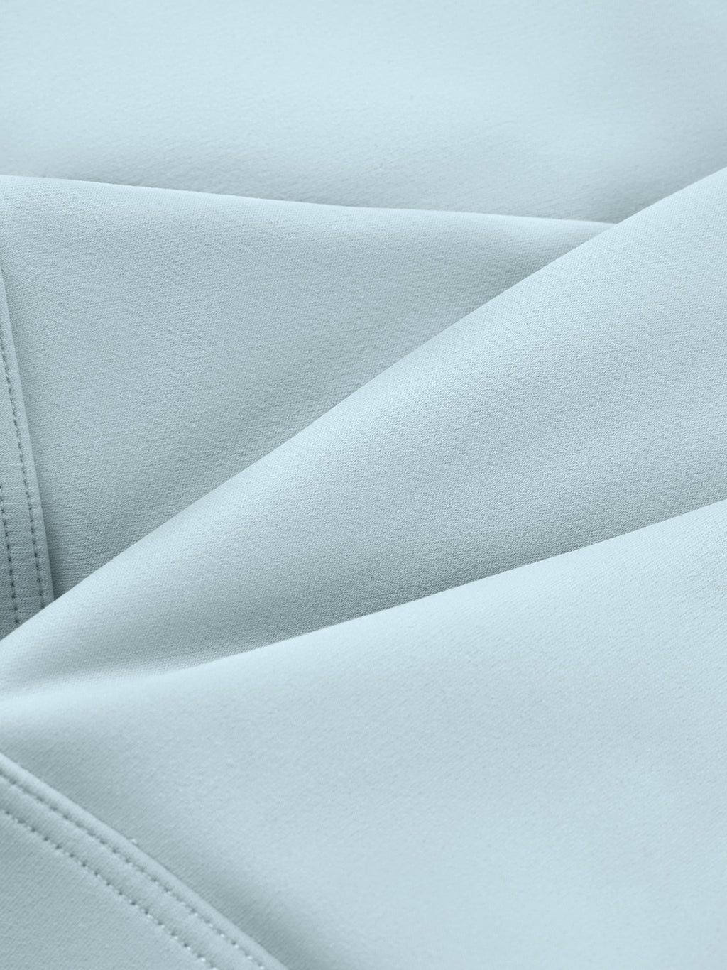 Close-up of light blue fabric with subtle folds and visible stitching, likely from a yoga sports bra.