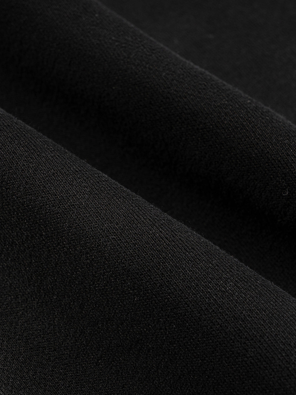 Close-up of thick black cotton blend fabric with subtle folds, showcasing its texture.