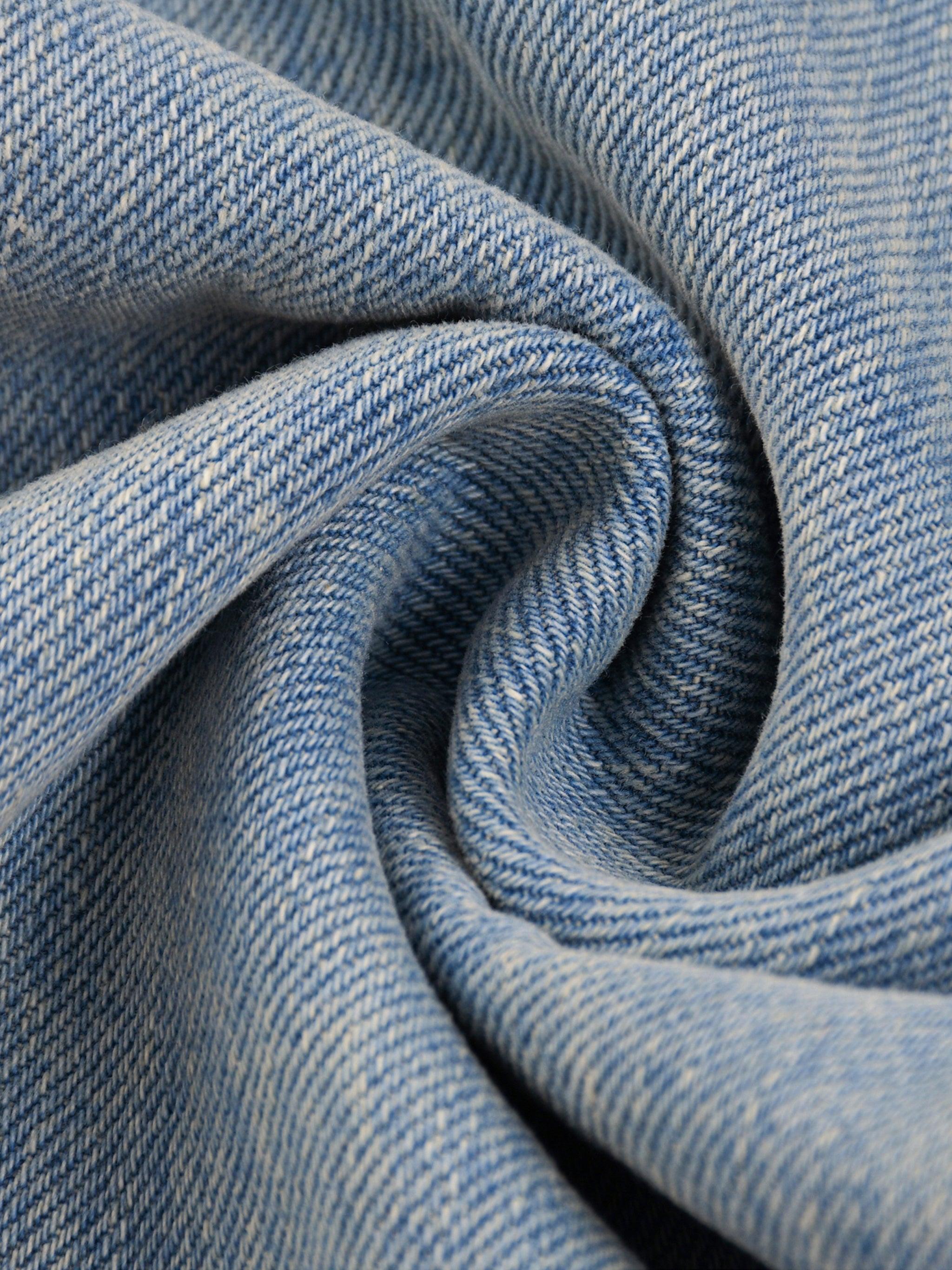 Close-up of sun fade raw hem denim jeans fabric, showing blue washed texture and weave.