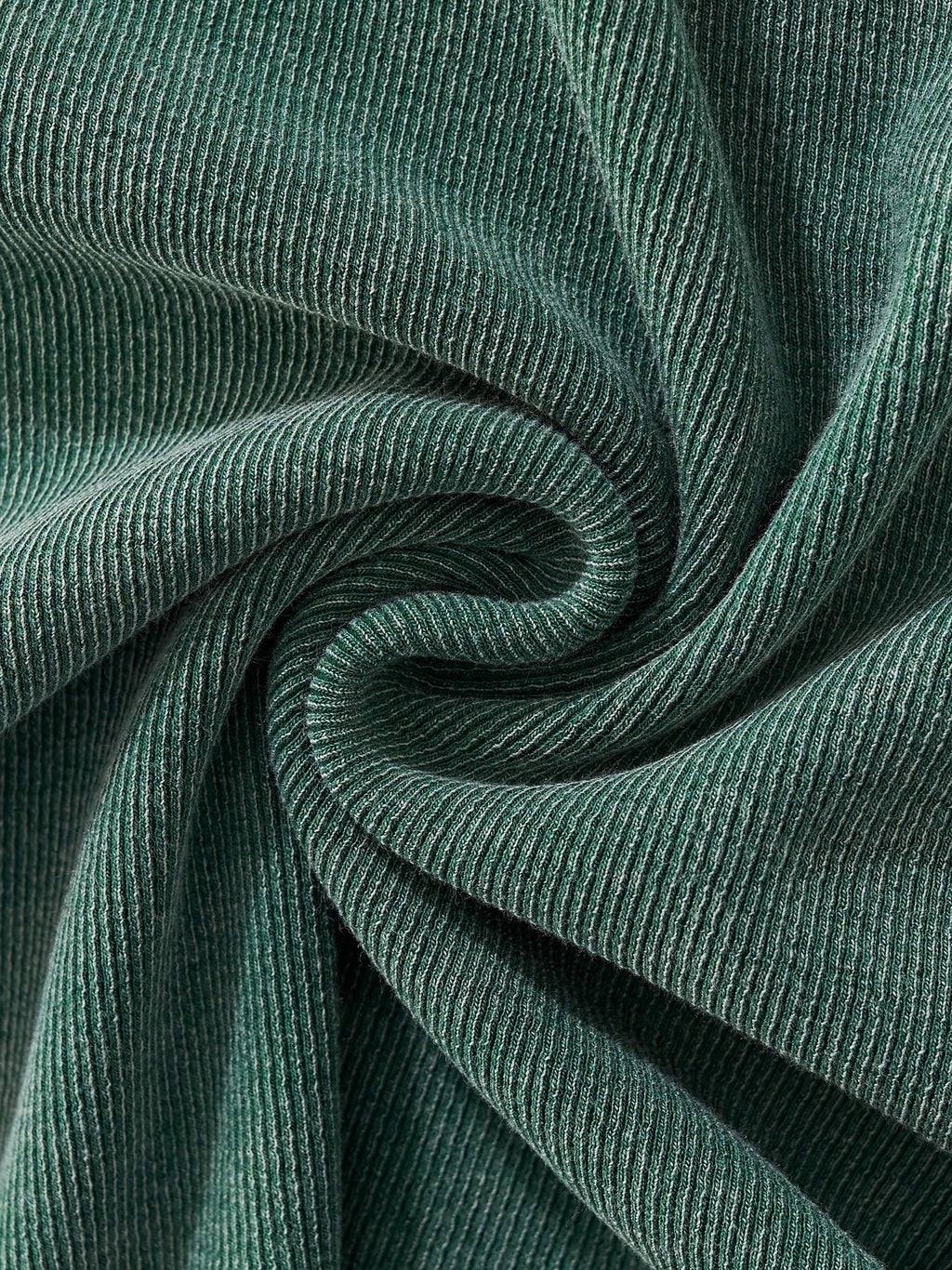 Close-up of a vintage washed, ribbed dark green cotton blend fabric with soft folds.